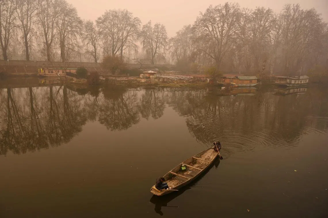 A boatman steers a boat along the Jehlum River during a foggy morning in Srinagar on November 30, 2022. 