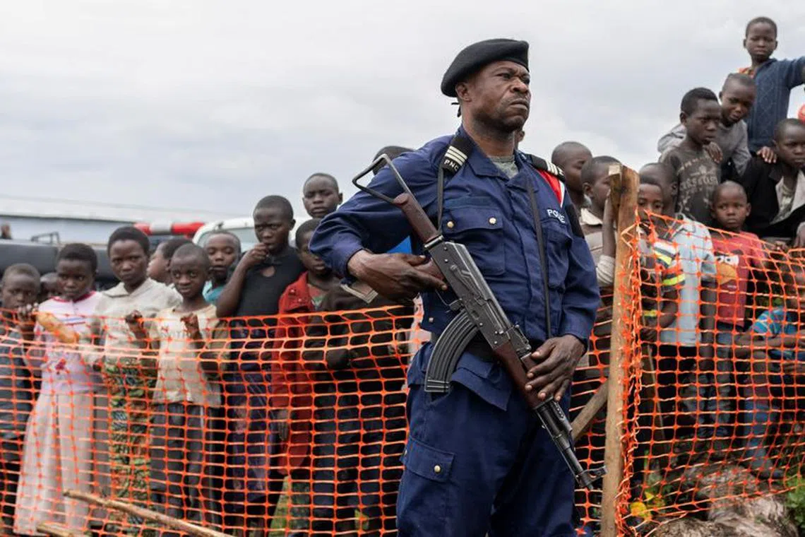 A Congolese police officer stands guard near internally displaced people gathered during the visit of a delegation of the U.N. Security Council at the Bushagara site near Goma in the North Kivu province of the Democratic Republic of Congo March 12, 2023. REUTERS/Arlette Bashizi/File Photo