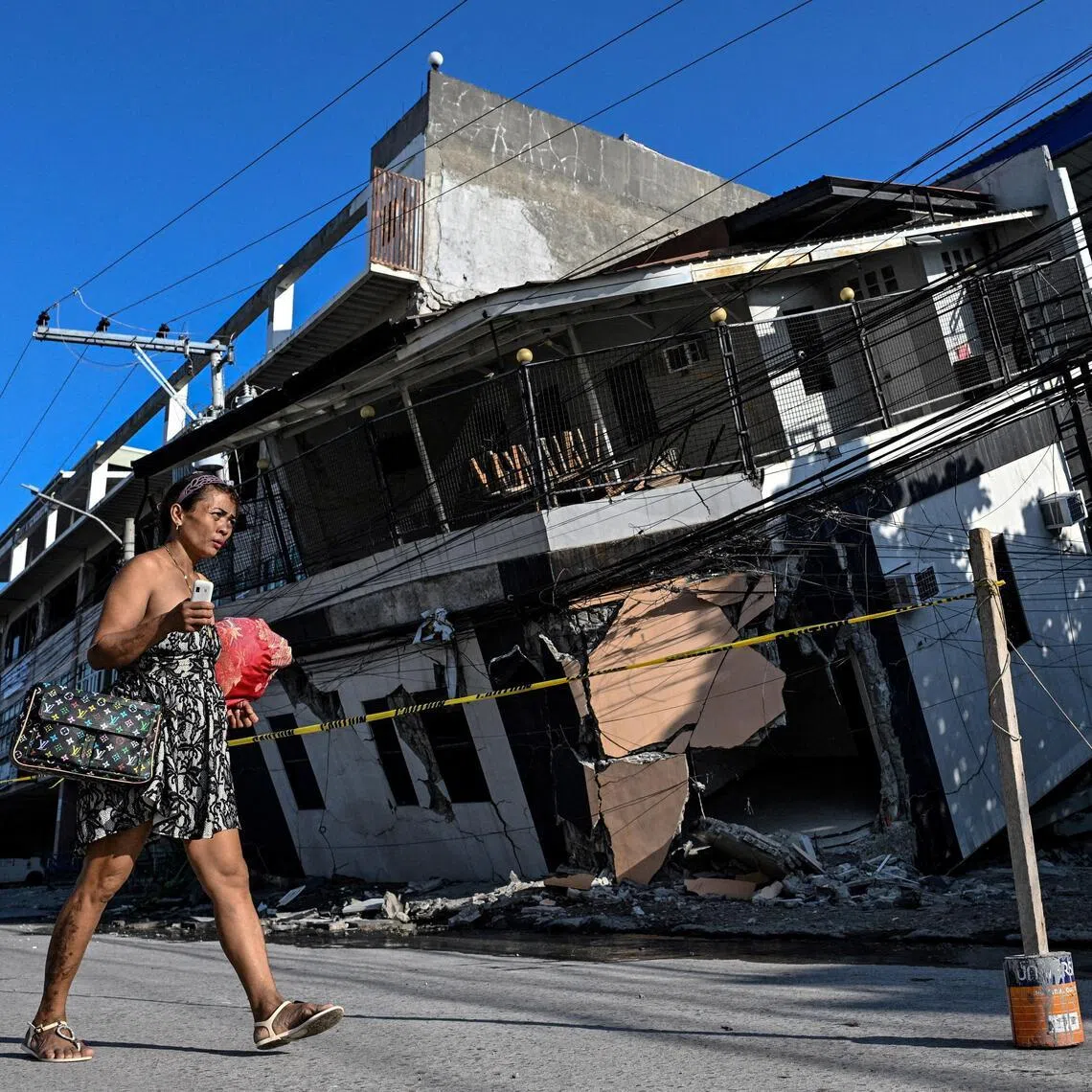 A woman walks past a collapsed building a day after a 7.8-magnitude quake struck southern Philippines on June 8.