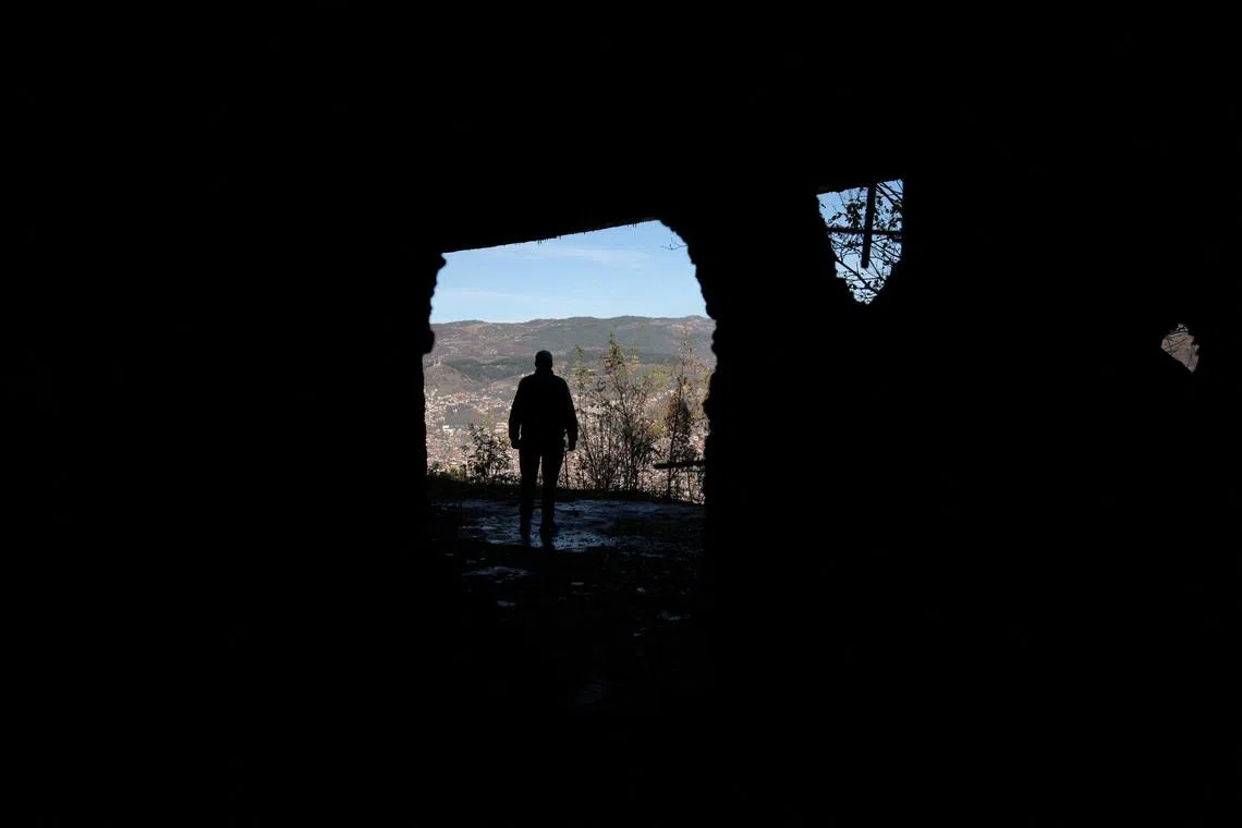 FILE PHOTO: A Bosnian worker looks out at Sarajevo through a hole in a war-damaged building that once marked the front line during the 1992–95 Bosnian War, in Sarajevo, Bosnia and Herzegovina, November 13, 2025. REUTERS/Amel Emric/File Photo