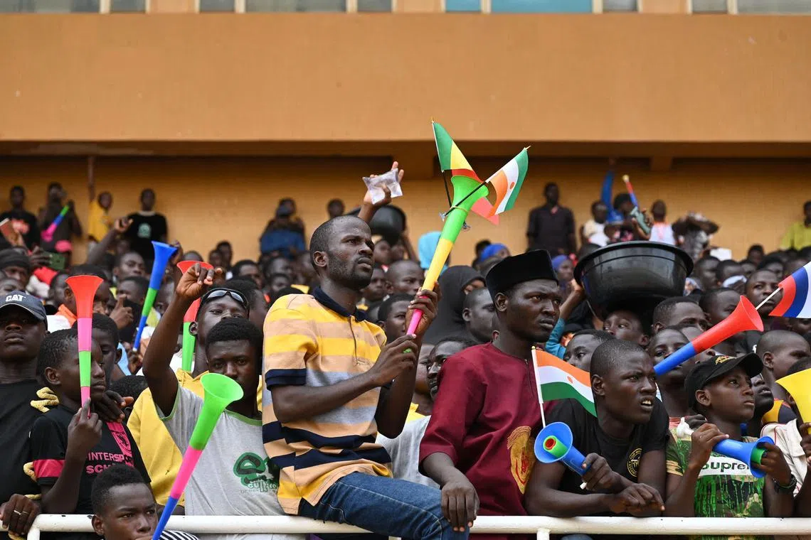 A man waves Niger, Mali and Burkina Faso flags as supporters cheer from the stands while artists perform during a concert in support to Niger's National Council for the Safeguard of the Homeland (CNSP) at the General Seyni Kountche Stadium in Niamey on August 13, 2023. (Photo by AFP)