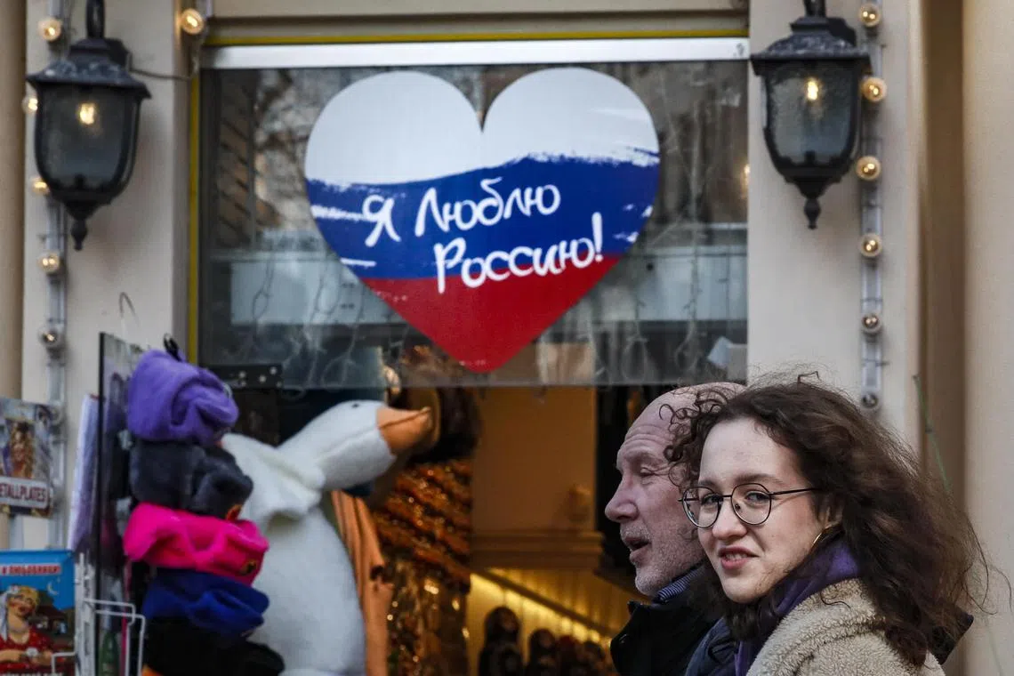 People walk past a gift shop decorated with a Russian flag in the form of a heart and the inscription "I love Russia", in central Moscow.