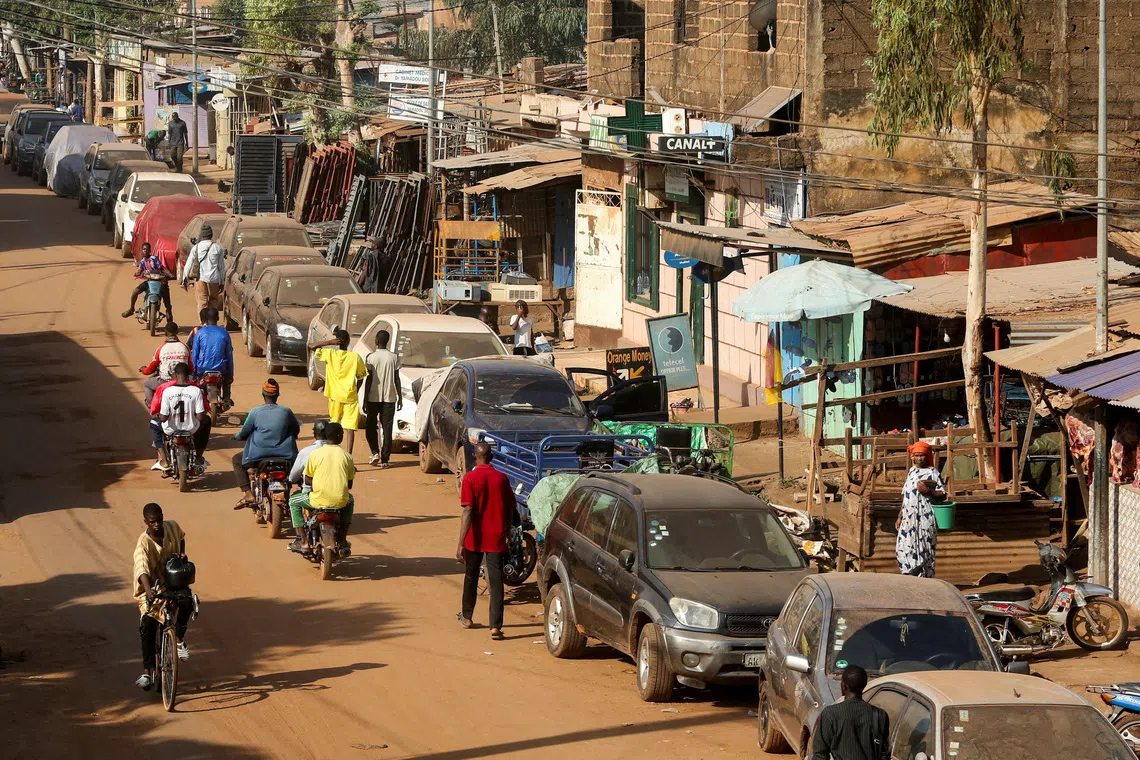 FILE PHOTO: A cyclist and motorcyclists pass by cars parked on the roadside amid ongoing fuel shortages caused by a blockade imposed by al Qaeda-linked insurgents in early September, in Bamako, Mali, October 31, 2025. REUTERS/Stringer/File Photo