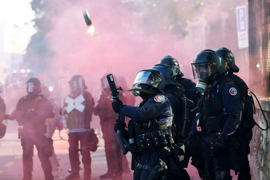 A riot police officer firing a weapon amid clashes with demonstrators, during a protest against the upcoming G7 summit, in Geneva, Switzerland, on June 14, 2026. 