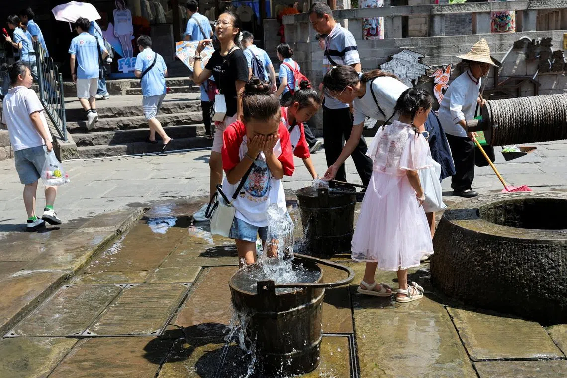 A child rinses her face with water from the fountain to cool off amid a red alert for heat in Chongqing, China July 31, 2025. REUTERS/Go Nakamura