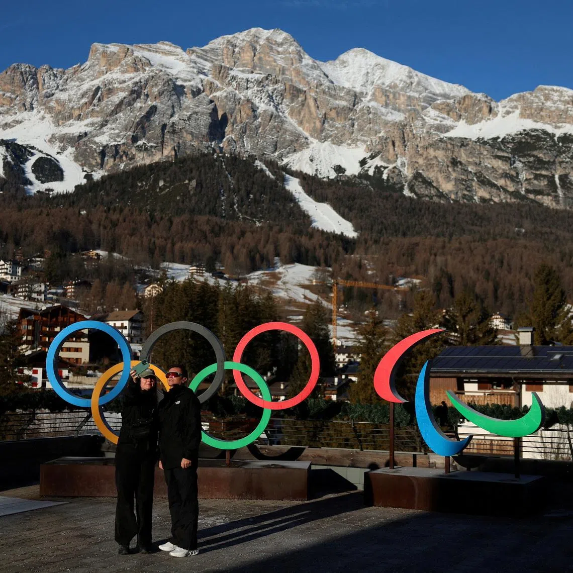 FILE PHOTO: People pose for a picture in front of the Olympic rings and the Olympia delle Tofane track, which will host the women's alpine skiing competition during the Milano Cortina Winter Olympic Games 2026, in Cortina, Italy, January 24, 2025. REUTERS/Claudia Greco/File Photo