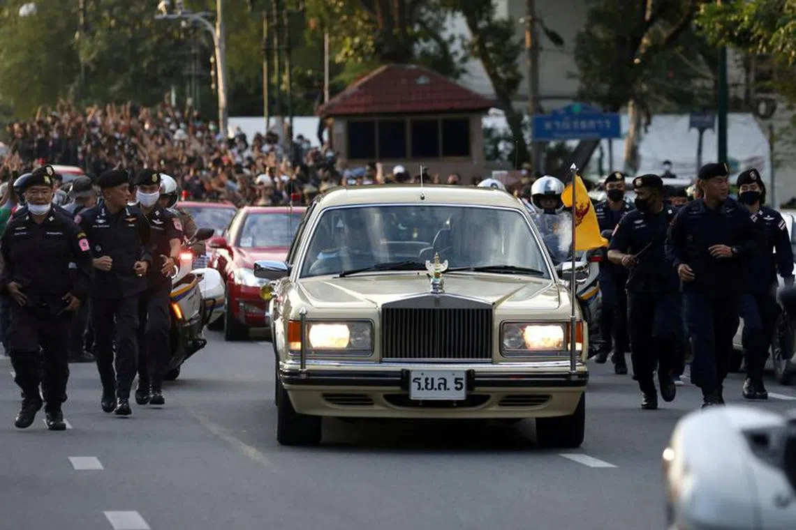 FILE PHOTO: The royal motorcade carrying Thailand's Queen Suthida and Prince Dipangkorn drives past a group of anti-government demonstrators in front of Government House, on the 47th anniversary of the 1973 student uprising, in Bangkok, Thailand October 14, 2020. REUTERS/Soe Zeya Tun/File Photo