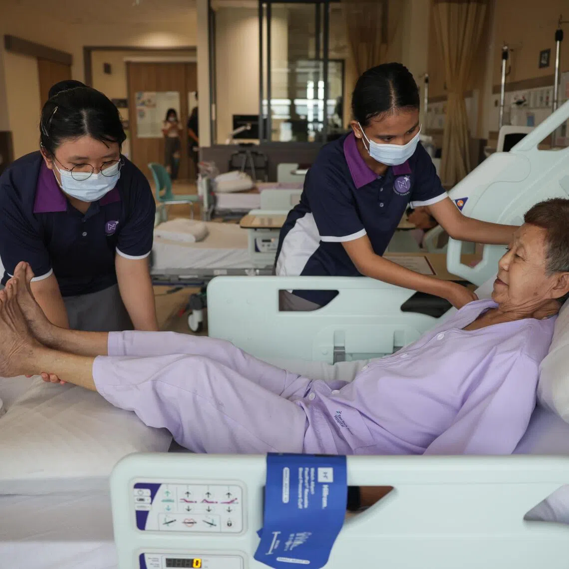 NorthLight School students Esther Kuan Yi Lin (left) and Puteri Ellysha Misram tending to a patient during a demonstration at the orthopaedic and general surgical ward in the TTSH Integrated Care Hub on June 30.