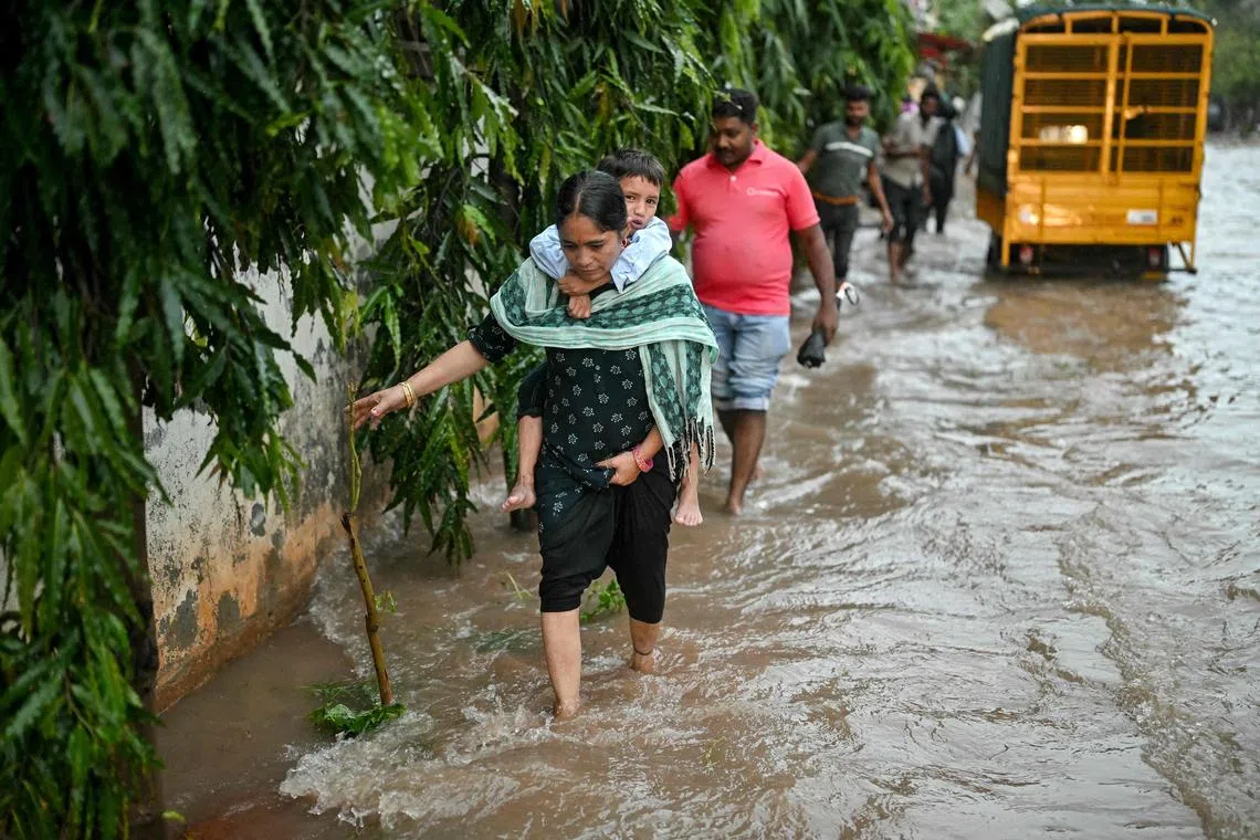 People wade through a flooded street following heavy rainfall in Bengaluru on Oct 15, 2024.
