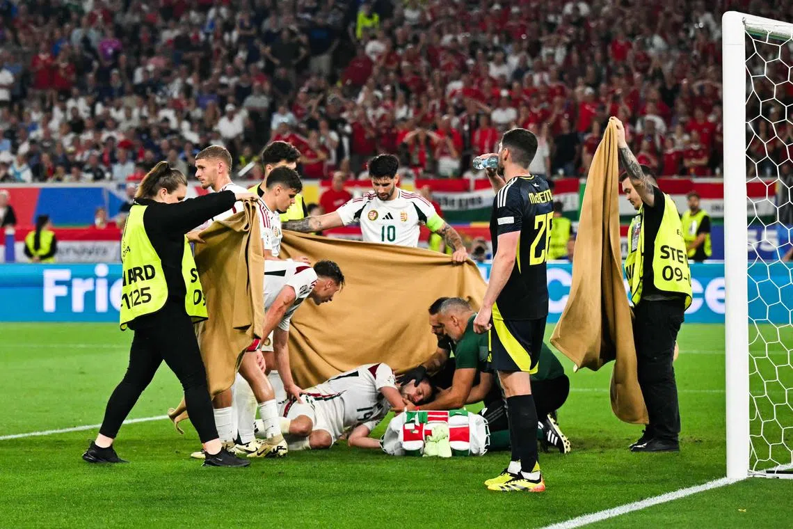 Players and stewards hold a cloth as Hungary's forward Barnabas Varga falls after a collision during the Euro 2024 Group A football match between Scotland and Hungary at the MHPArena in Stuttgart on June 23.