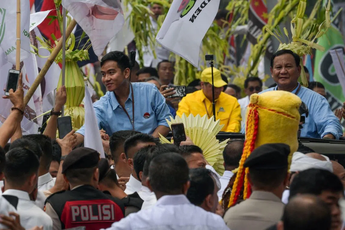 Presidential candidate and incumbent Defense Minister Prabowo Subianto  (R) and vice presidential candidate and incumbent Solo Mayor Gibran Rakabuming Raka (L), who is also the son of President Joko Widodo, greet their supporters as they register as candidates at the General Election Commission in Jakarta on October 25, 2023. (Photo by BAY ISMOYO / AFP)