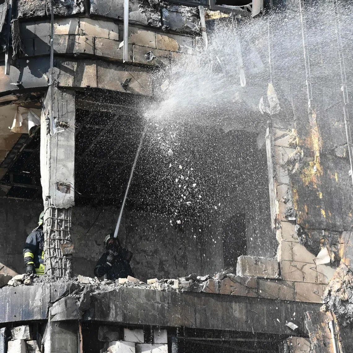 Ukrainian rescuers work to extinguish a fire in a damaged residential building following a drone attack in Kharkiv.