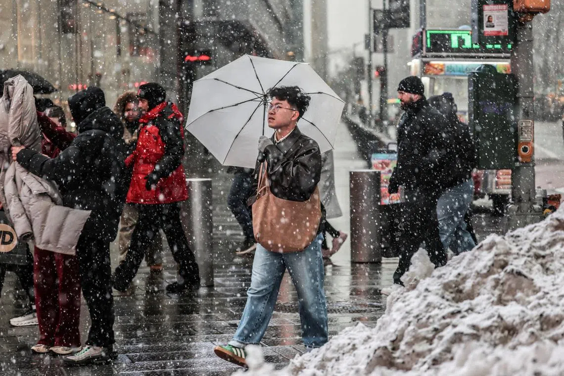 People walk on a street as snow falls during a winter storm in New York City, U.S., February 22, 2026.  REUTERS/Jeenah Moon