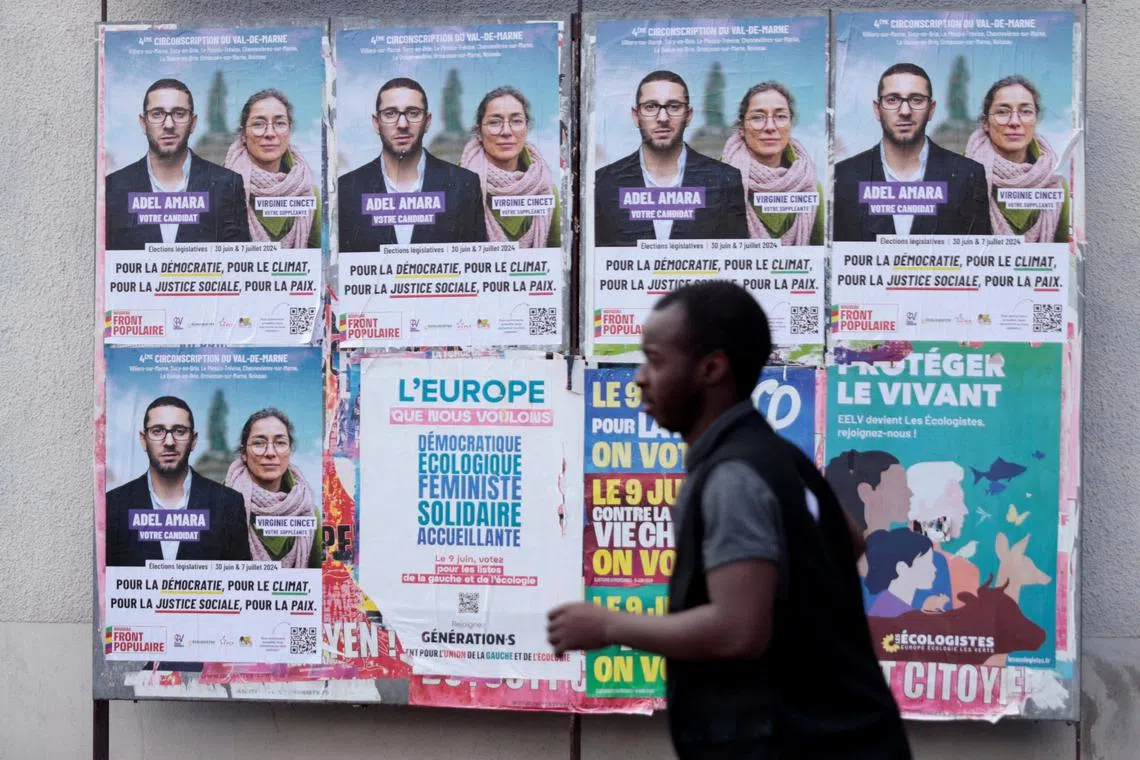 FILE PHOTO: A man walks past campaign posters for Adel Amara, candidate for the French left wing alliance, named the New Popular Front (Nouveau Front Populaire - NFP), for the upcoming French parliamentary elections, in Le Plessis-Trevise near Paris, France, June 19, 2024. REUTERS/Abdul Saboor/File Photo