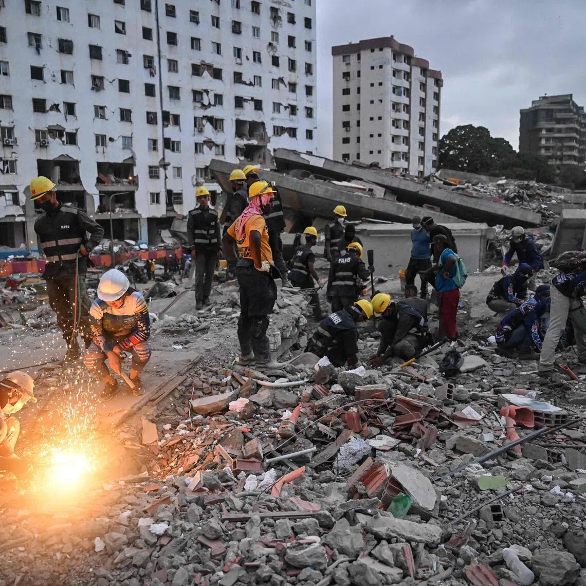 Volunteers and rescuers search for bodies amid debris of buildings damaged by the earthquakes, in La Guaira, Venezuela, on July 18.