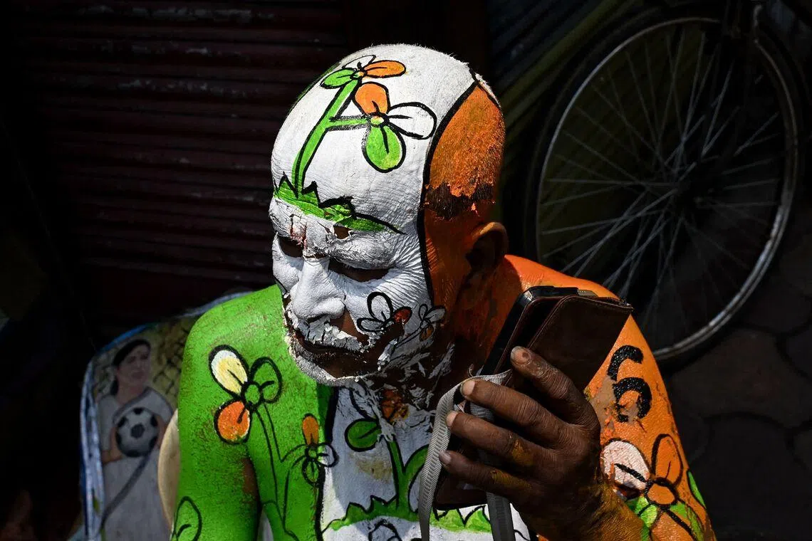 A supporter with the All India Trinamool Congress (TMC) party election symbol painted on his body uses his mobile phone along a street near the residence of West Bengal chief minister and party chairperson Mamata Banerjee in Kolkata on May 4, 2026 during vote counting for the West Bengal Legislative Assembly elections. Vote counting in key Indian state elections was underway on May 4 under tight security, with the focus on West Bengal, where Prime Minister Narendra Modi's party appeared set for victory. (Photo by Dibyangshu SARKAR / AFP)