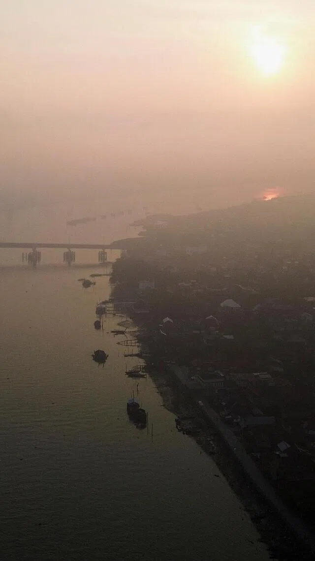 A drone view shows a residential area along the Musi river as smog covers it due to recent wildfires in Palembang, South Sumatra province, Indonesia, August 11, 2026. REUTERS/Abriansyah Liberto