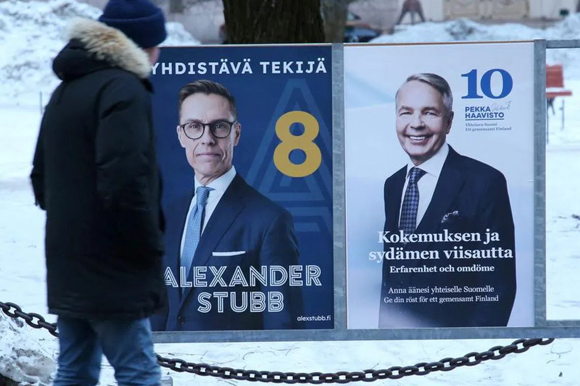 A pedestrian stands next next to posters of Alexander Stubb and Pekka Haavisto, candidates in the second round of the Finnish presidential elections, in Helsinki, Finland, February 10, 2024. REUTERS/ Tom Little