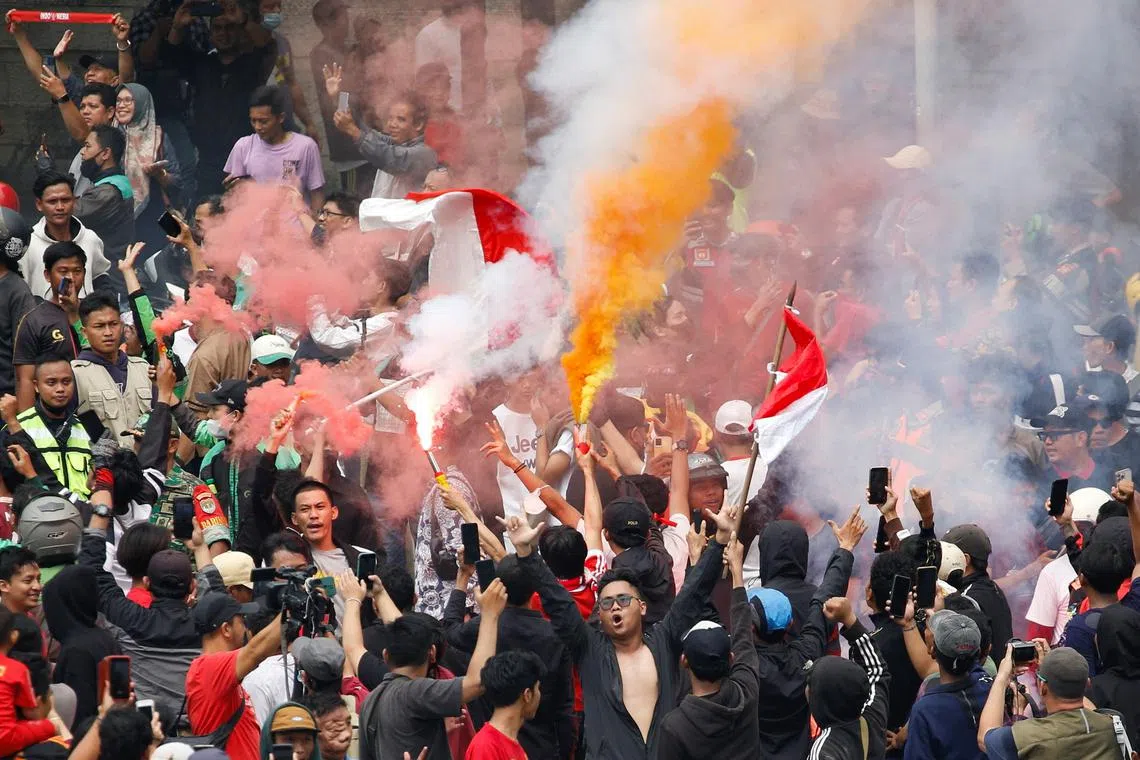 Indonesian football supporters light flares during a parade in Jakarta, as they celebrate their football team winning gold at the SEA Games 2023.