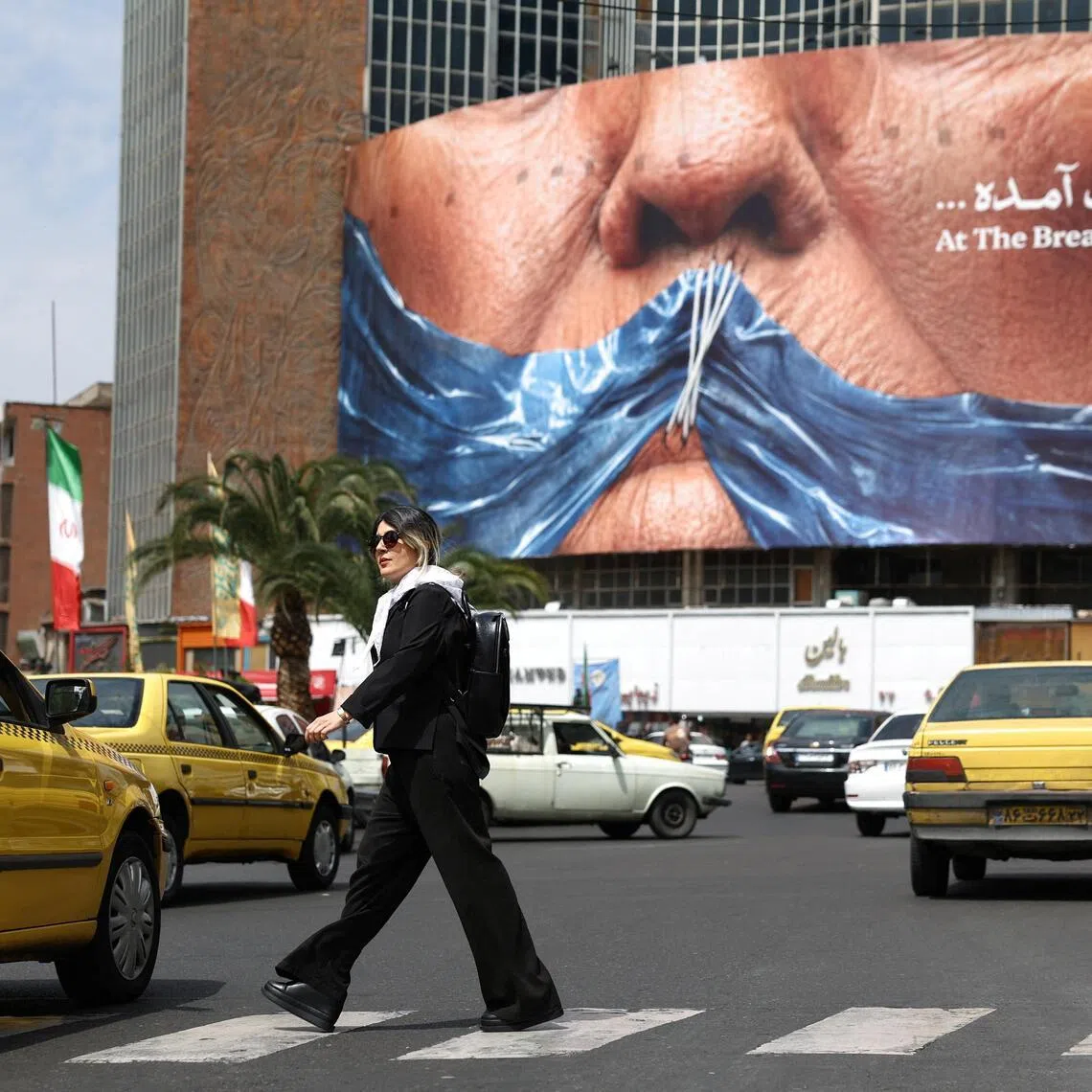A woman walks past an anti-US billboard depicting US President Donald Trump and the Strait of Hormuz, in Tehran, Iran, on May 2, 2026.