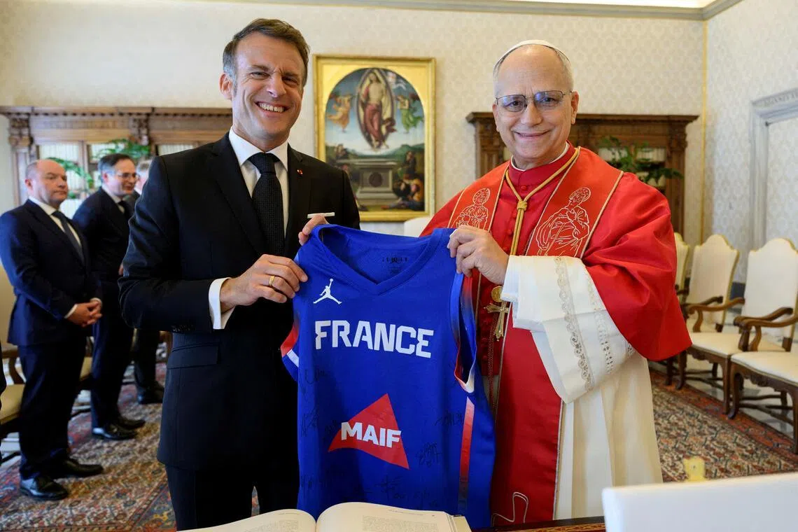French President Emmanuel Macron and Pope Leo XIV hold a sport shirt as they meet at the Vatican, on April 10, 2026.