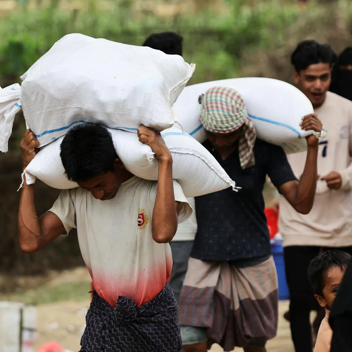 Rohingya refugees carry rice sacks that they receive as ration from the World Food Program(WFP), at a refugee camp in Cox's Bazar, Bangladesh, April 18, 2026. REUTERS/Mohammad Ponir Hossain