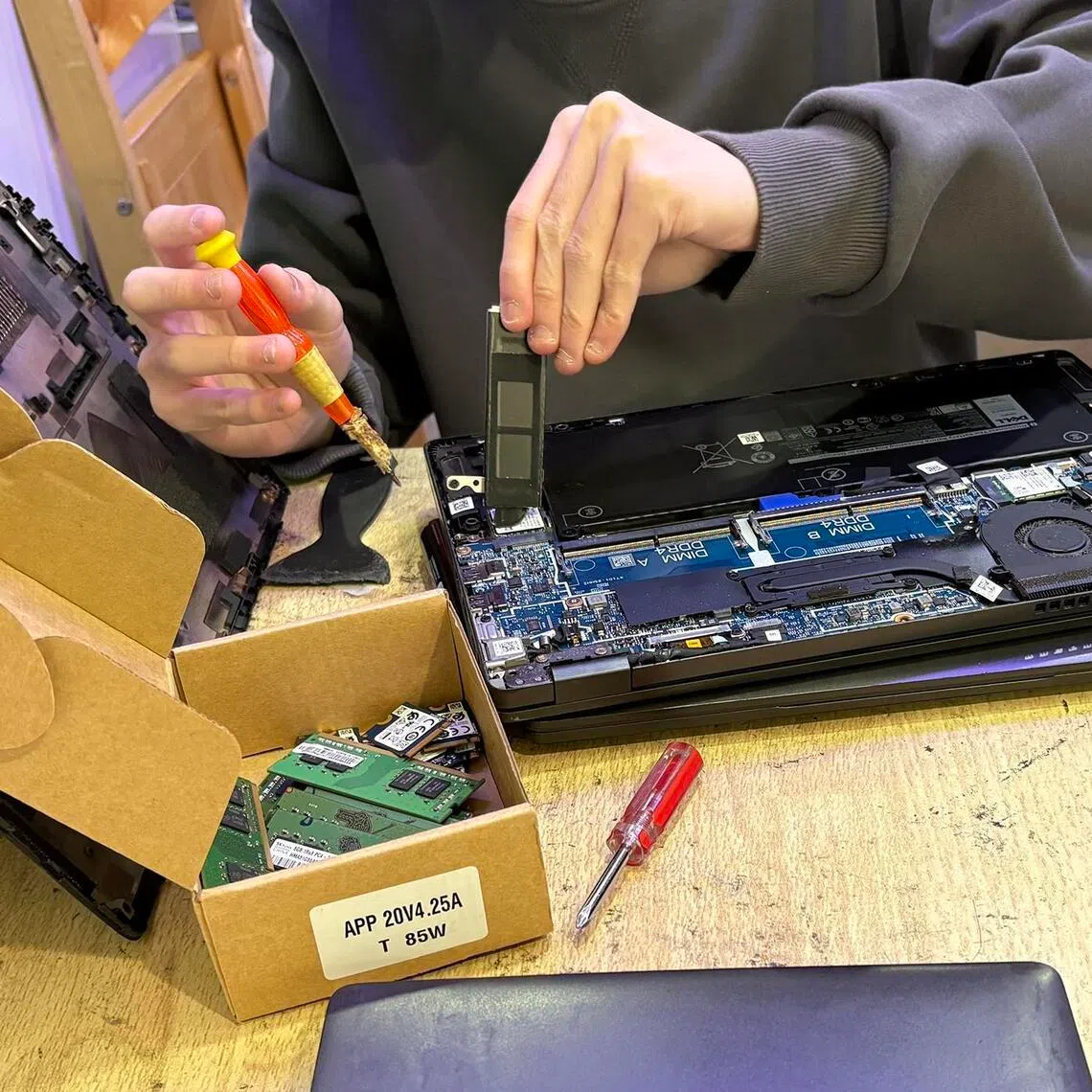 A worker removes a memory chip from a laptop at a shop at Sim Lim Square on Feb 24, 2026.