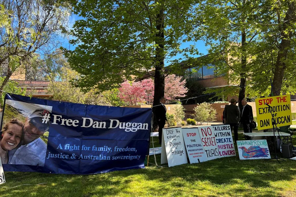 FILE PHOTO: People interact near signs placed during a demonstration in support of former U.S. Marine Corps pilot Daniel Duggan outside the Federal Court of Australia, on the day Duggan appeals against extradition to the U.S. on charges of violating U.S. arms control laws related to China, in Canberra, Australia, October 16, 2025. REUTERS/Peter Hobson/File Photo
