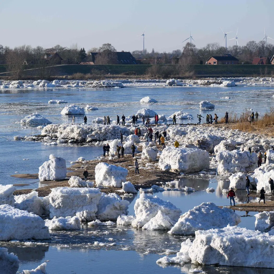 Onlookers make their way through large chunks of ice and ice floes washed up along the banks of the Elbe river near Geesthacht, northern Germany.
