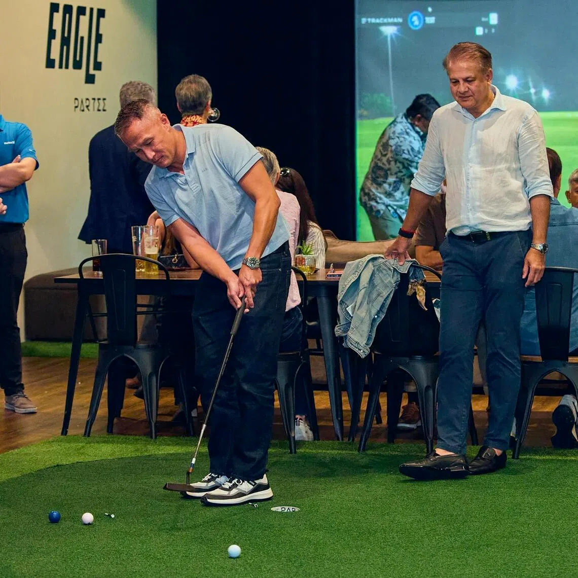 Hugo Boss vice-captain John Lim trying his luck at the putting contest watched by Singapore Pools’ Alan Soon (left) and Seagull Marine’s Yogi Tewani (right) during the networking event at Partee Golf at Science Park Drive on Feb 11. 