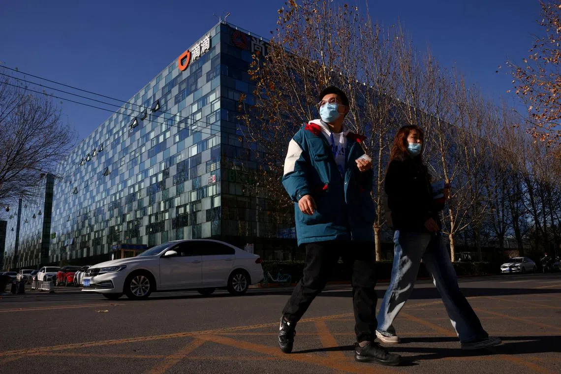 FILE PHOTO: People walk past the headquarters of the Chinese ride-hailing service Didi in Beijing, China, December 3, 2021. REUTERS/Thomas Peter/File Photo/File Photo