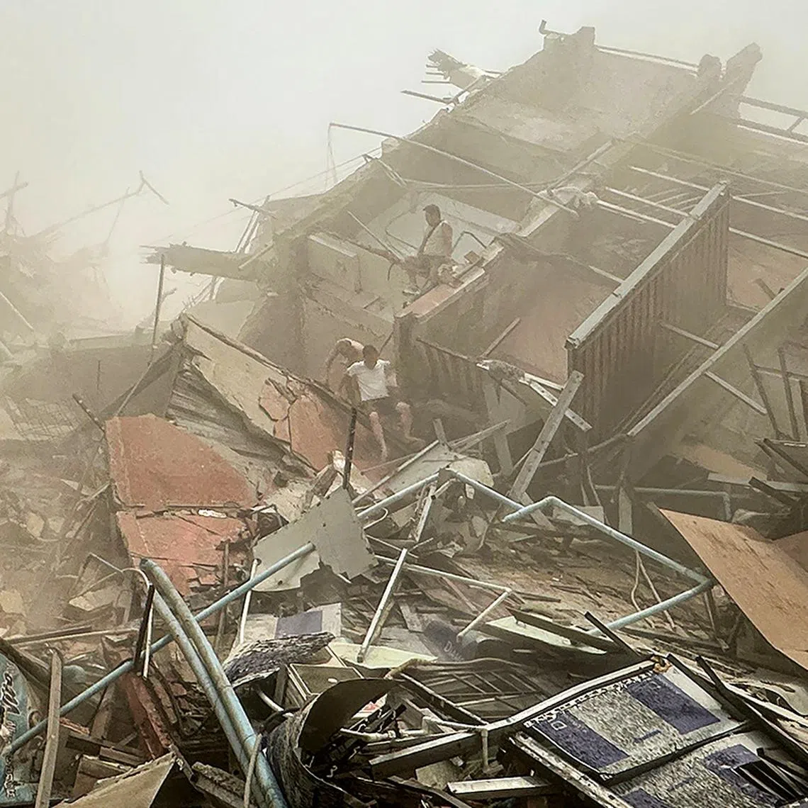 TOPSHOT - People inspect the debris of a collapsed building in Mandalay on March 28, 2025, after an earthquake. A powerful earthquake killed more than 20 people across Myanmar and Thailand on March 28, toppling buildings and bridges and trapping over 80 workers in an under-construction skyscraper in Bangkok. (Photo by AFP)