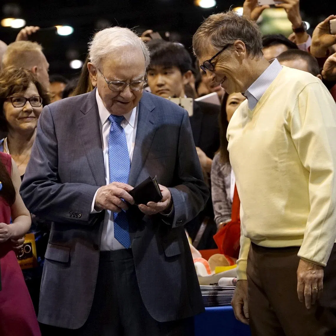 Berkshire Hathaway CEO Warren Buffett (L) gets his wallet out to pay a bet to Microsoft co-founder Bill Gates after participating in a newspaper throwing contest prior to the Berkshire annual meeting in Omaha, Nebraska May 2, 2015.  REUTERS/Rick Wilking