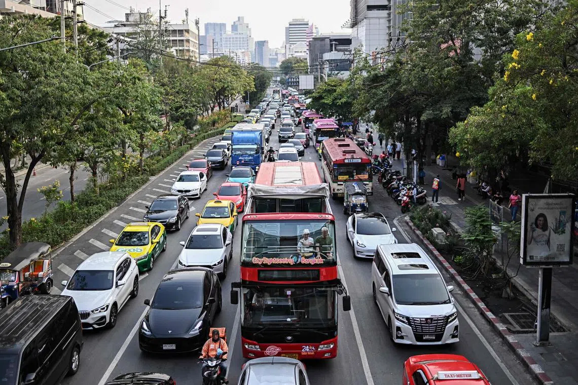 Tourists sit on top of a sightseeing tour bus while stuck in afternoon traffic in Bangkok on March 21, 2024. 