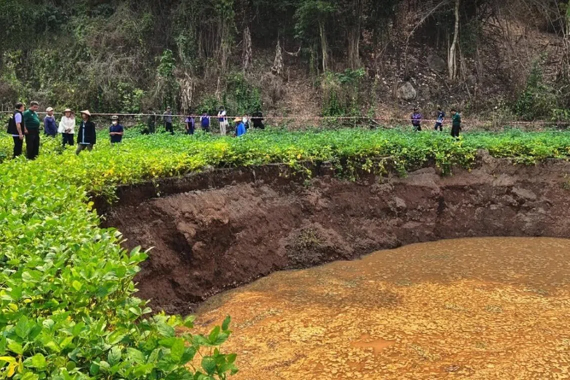 The authorities survey a large sinkhole that emerged at a farm in Mae Hong province.