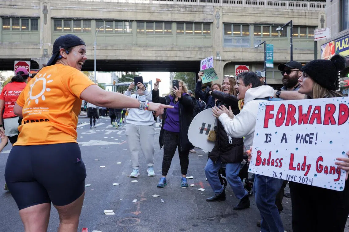A competitor pointing at a sign  during the 2024 New York City Marathon on Nov 3.  An expert says simply exploring running, at any speed, for any length or interval, is a worthy goal in itself.