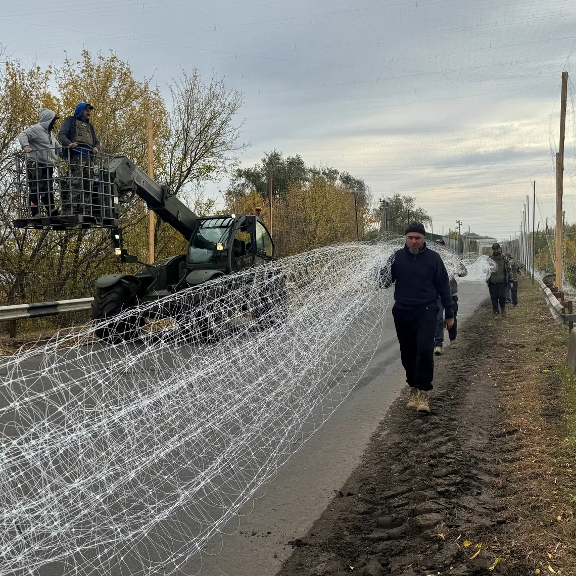 Ukrainian servicemen install anti-drone nets over a road, amid Russia's attack on Ukraine, near the frontline town of Dobropillia in Donetsk region, Ukraine October 8, 2025. REUTERS/Stringer