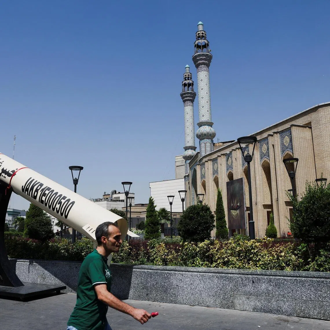 A man walks next to a mock-up of an Iranian missile on a street in Tehran, Iran.
