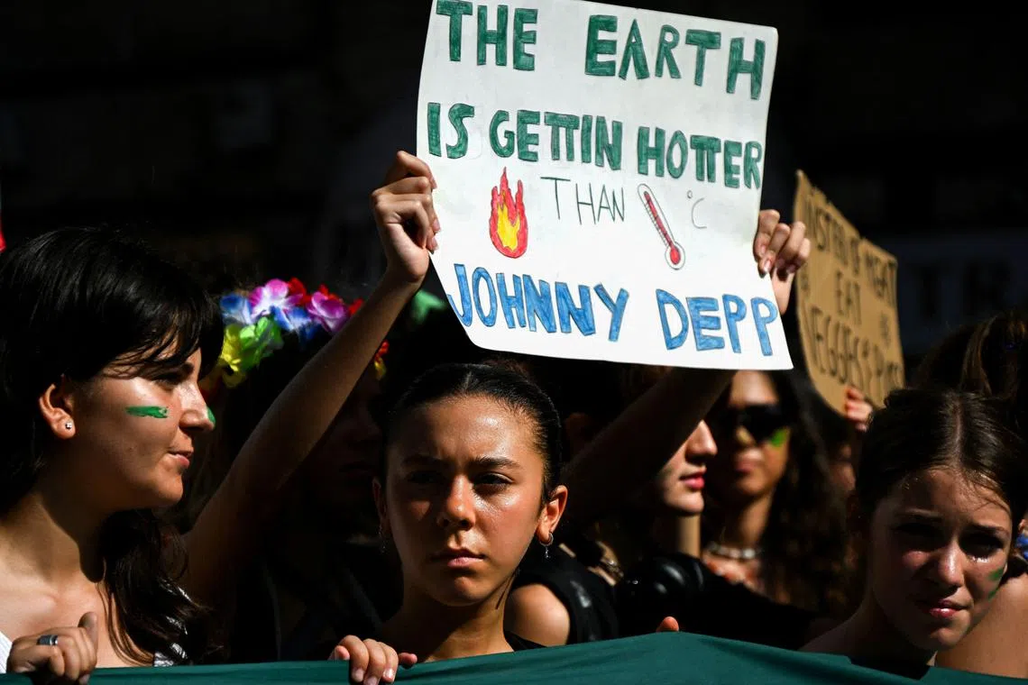 A demonstrator holds a placard during a youth protest march on climate change in downtown Rome on October 6, 2023. (Photo by Filippo MONTEFORTE / AFP)