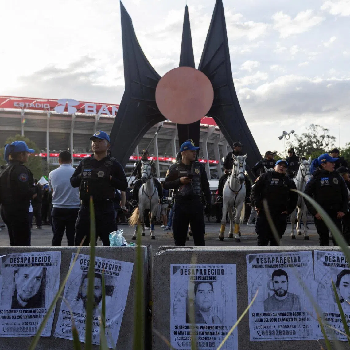 Police officers, including mounted police, stand guard near posters of missing people as relatives of victims of forced disappearance protest outside Azteca Stadium in Mexico City.