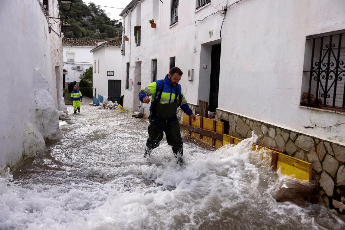 Workers walk along a flooded street after heavy rains, as Storm Marta hits parts of Spain, in Ubrique, Spain, February 8, 2026. REUTERS/Jon Nazca