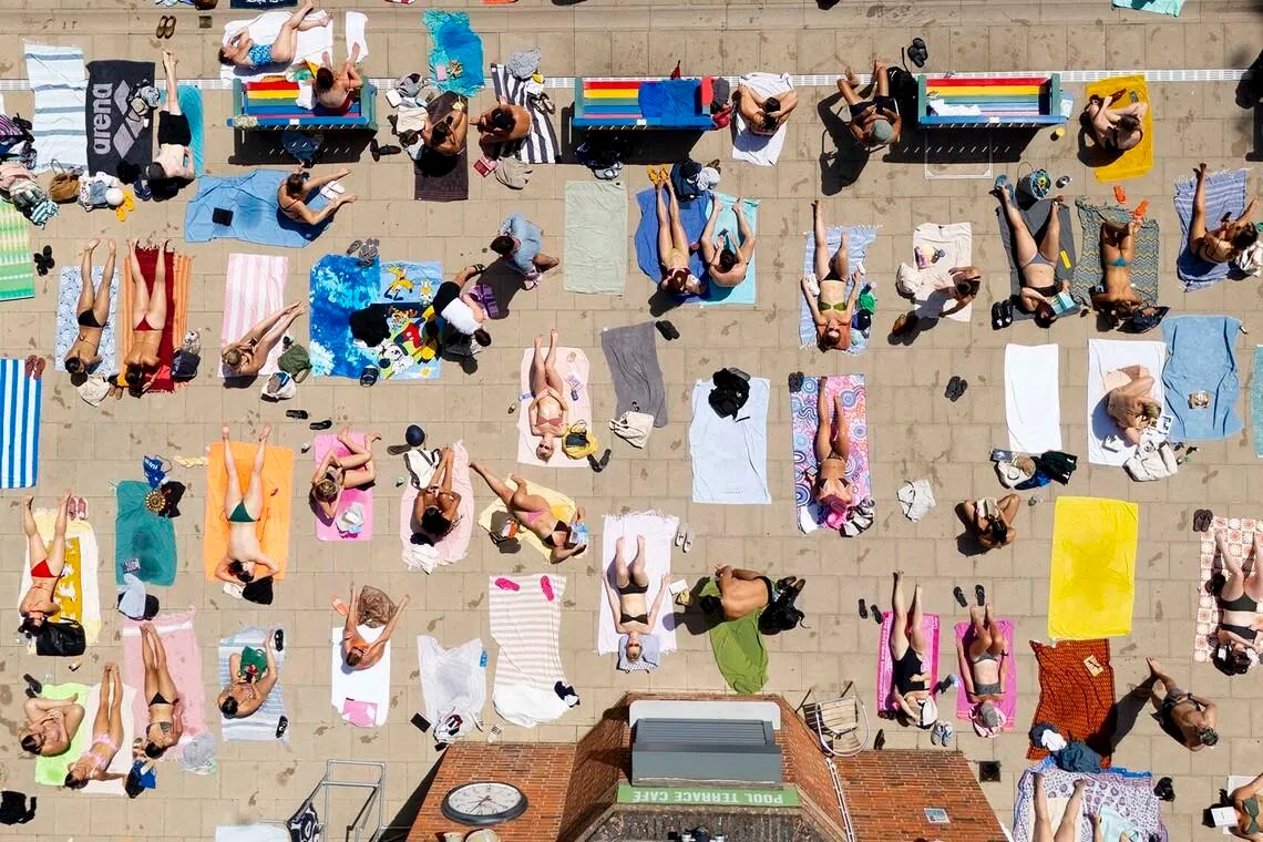 People sunbathing at London Fields Lido outdoor swimming pool as Britain faced forecast record June temperatures amid a heatwave in London, Britain, on June 23. 
