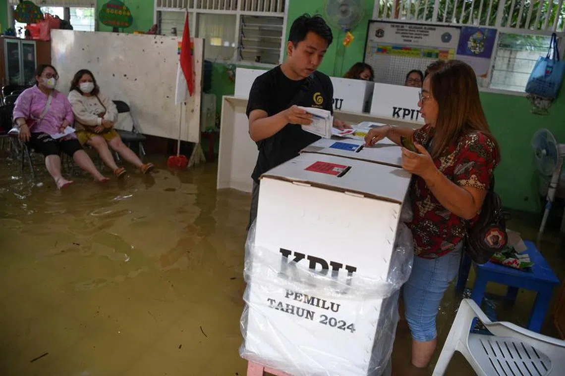 Voters cast their ballots at a flooded polling station during general election in Jelambar, West Jakarta, Indonesia February 14, 2024. Antara Foto/Wahyu Putro A via REUTERS