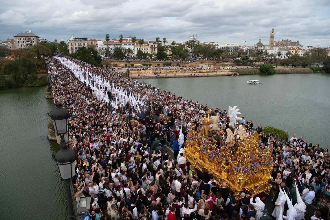 A crowd packs Triana Bridge as people gather to watch the San Gonzalo brotherhood crossing during the Holy Monday procession in Seville on April 14, 2025. Christian believers around the world mark the Holy Week of Easter in celebration of the crucifixion and resurrection of Jesus Christ. 