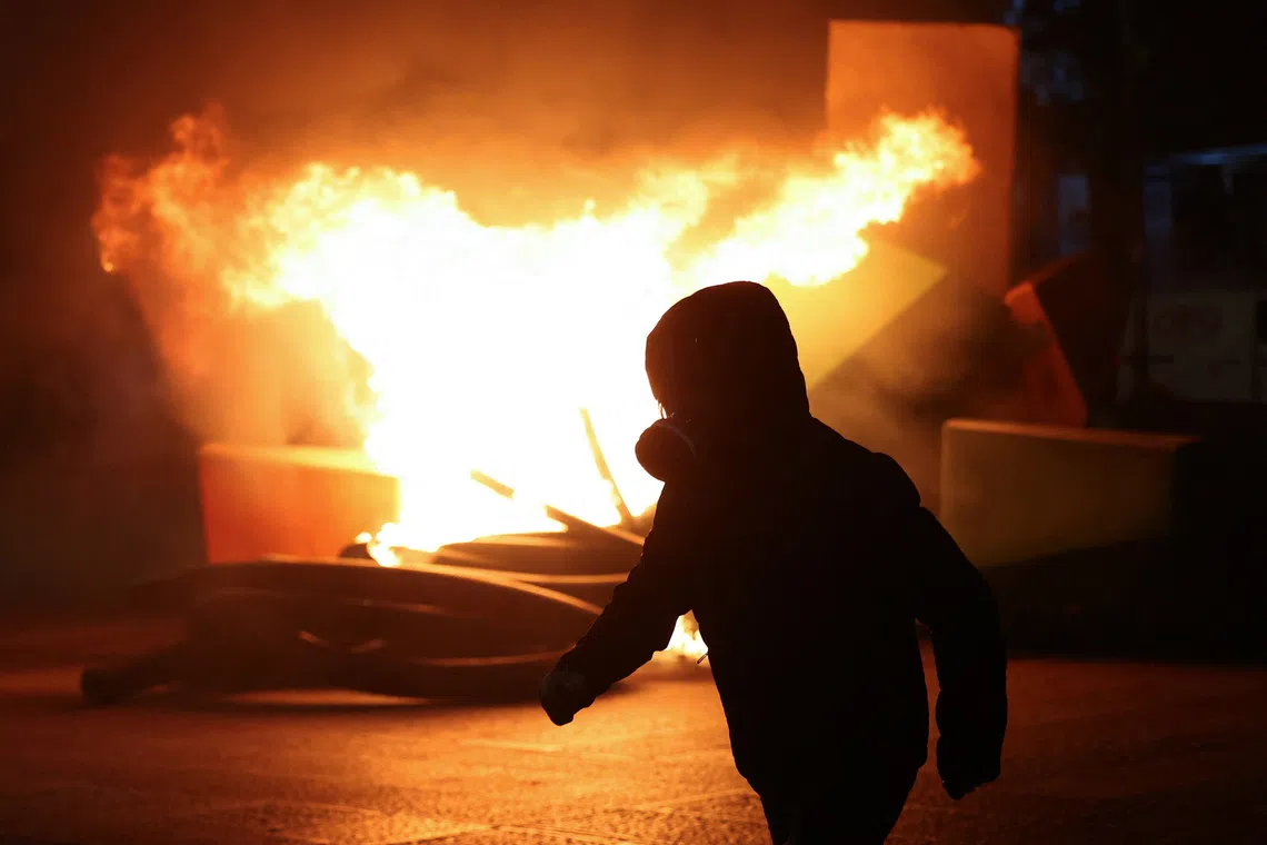 A demonstrator walks with flames burning in the background, amid an anti-government protest by students in Tirana, Albania, October 16, 2026. REUTERS/Florion Goga