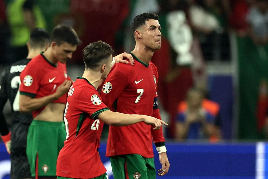 Cristiano Ronaldo being comforted by teammates after missing a penalty in extra time during their Euro last-16 game with Slovenia.
