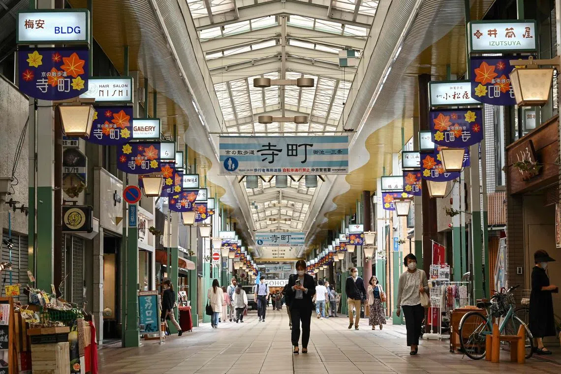 People walk along a popular covered shopping street in central Kyoto on October 13, 2022. (Photo by Richard A. Brooks / AFP)
