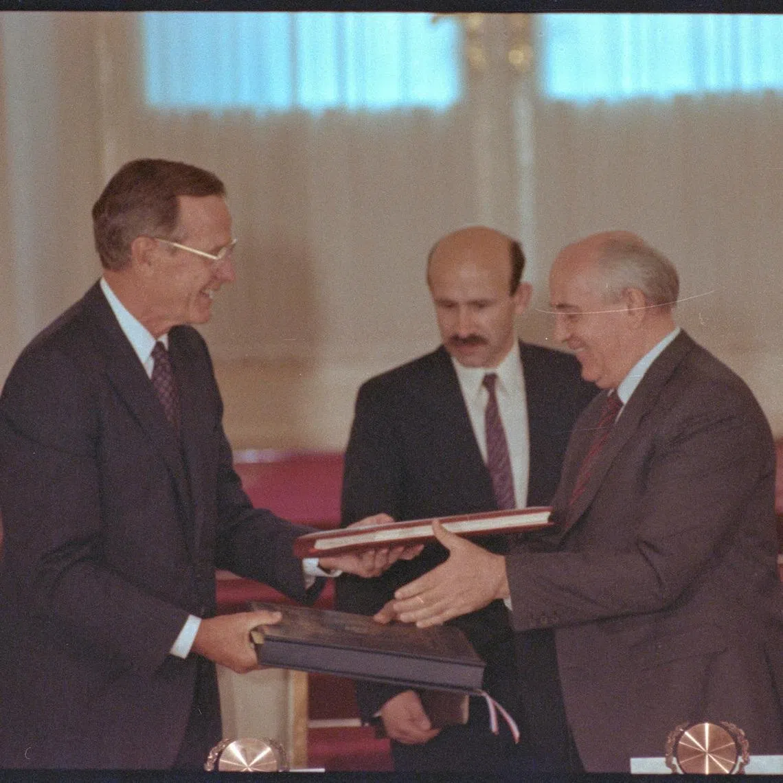 FILE PHOTO: US President George Bush and Soviet President Mikhail Gorbachev exchange documents after signing the START arms reduction treaty.  July 31, 1991 REUTERS/Larry Rubenstein   DISCLAIMER: The image is presented in its original, uncropped, and untoned state. Due to the age and historical nature of the image, we recommend verifying all associated metadata, which was transferred from the index stored by the Bettmann Archives, and may be truncated./File Photo