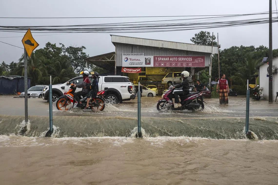 Residents drive through a flooded area during rainfall after a flash flood in Shah Alam, outside Kuala Lumpur, on Oct 3.