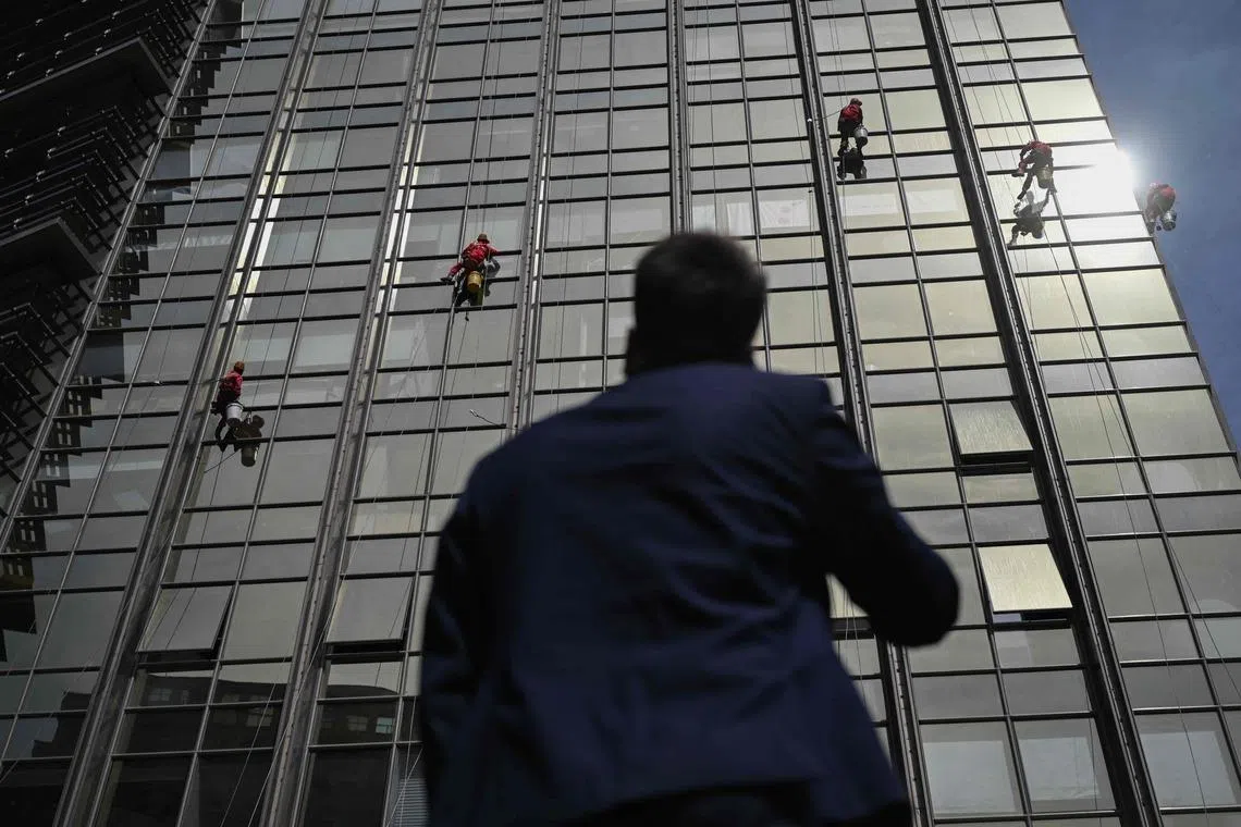 Workers cleaning the glass facade of a high-rise building in Beijing on April 21, 2026. 